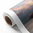 Rolled canvas depicting a serene beach landscape with soft waves and a vibrant sunset, elegantly packaged in a protective cardboard tube for easy transport.