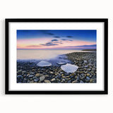 Black-framed landscape artwork depicting serene beaches with a mat, showcasing vibrant colors and a calming atmosphere, ideal for home decor or office setting.