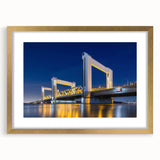 Abstract art print of Amsterdam scenery in muted gold and blue tones, framed with a gold mat, suitable for dining room decor.