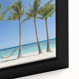 Close-up of a vibrant framed canvas artwork depicting a serene beach landscape with soft waves and a colorful sunset sky, perfect for coastal home decor.