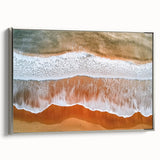 Framed canvas artwork depicting a tranquil beach scene with soft waves and golden sand, featuring a sleek silver frame, ideal for coastal home decor.