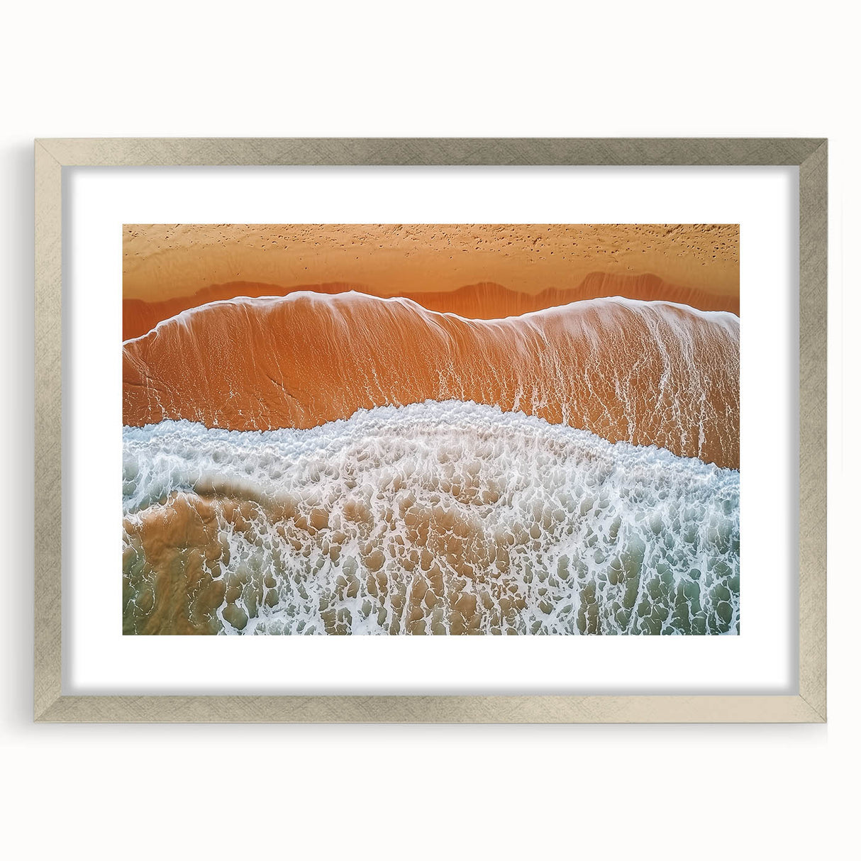 Framed landscape artwork showcasing a serene beach scene with gentle waves and a vibrant sunset, encased in a sleek silver frame with a white mat, perfect for coastal decor.