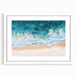 White-framed landscape artwork showcasing a serene beach scene with soft waves, vibrant blue skies, and gentle clouds, perfect for coastal-themed decor.