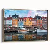 Framed canvas featuring a vintage-style landscape painting of a European scene in muted gold and black tones.