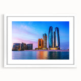Abstract art print of Abu Dhabi skyline in muted gray and blue tones on a framed white mat, ideal for dining room decor.