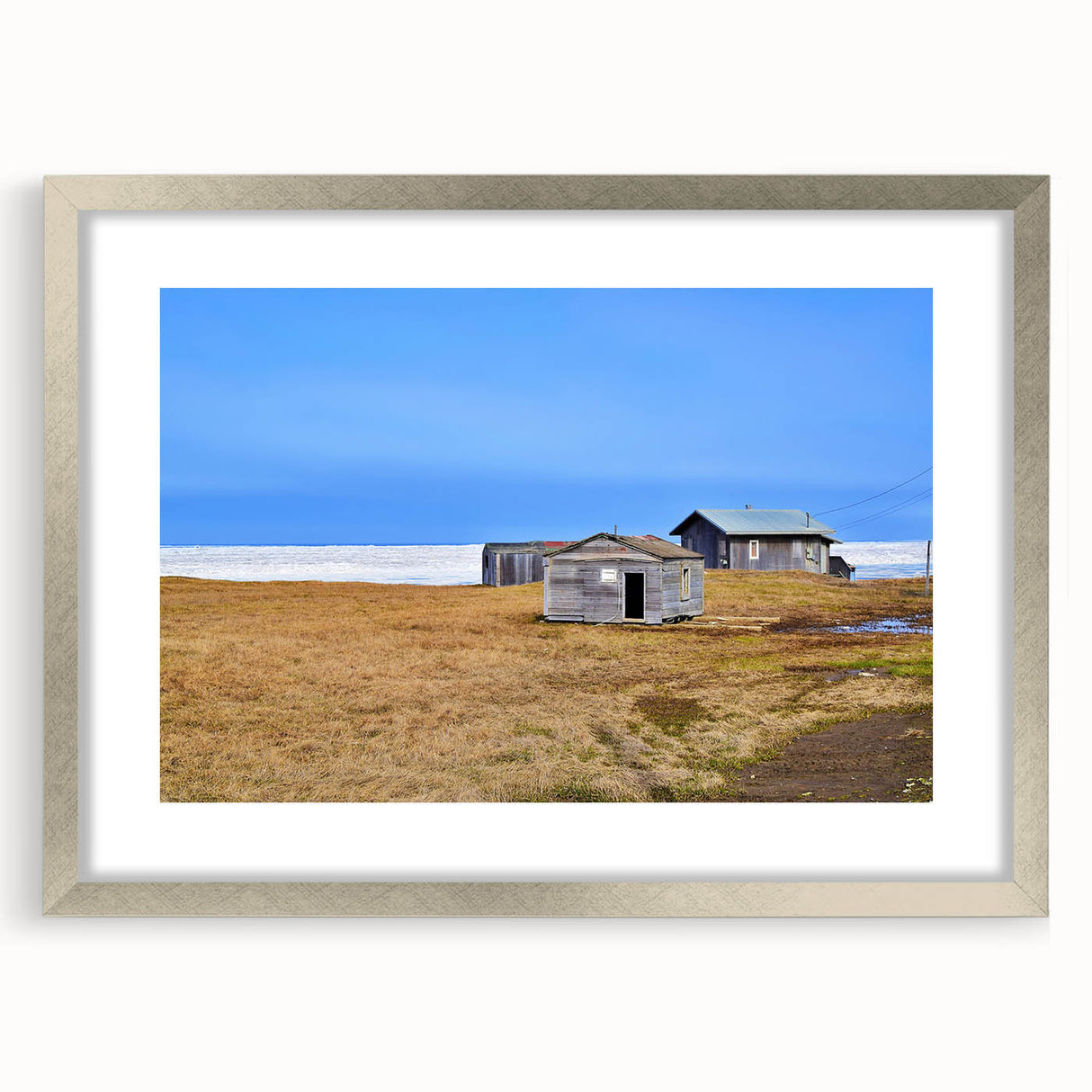 Textured abstract art print of an Alaskan landscape in muted earth tones on a framed silver mat, suitable for bedroom decor.