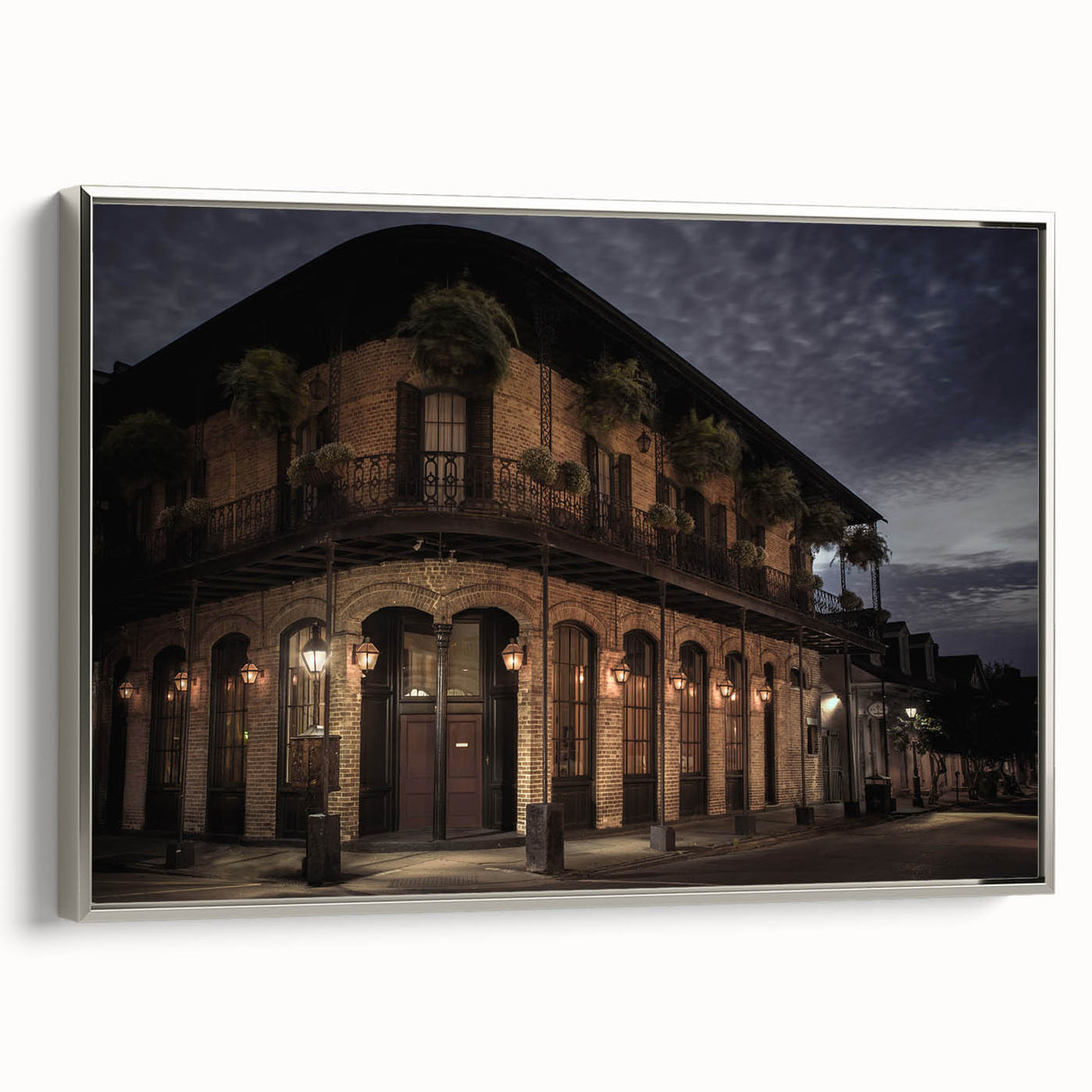 Landscape art painting of New Orleans with colorful buildings and a black sky, printed on a silver-framed canvas.