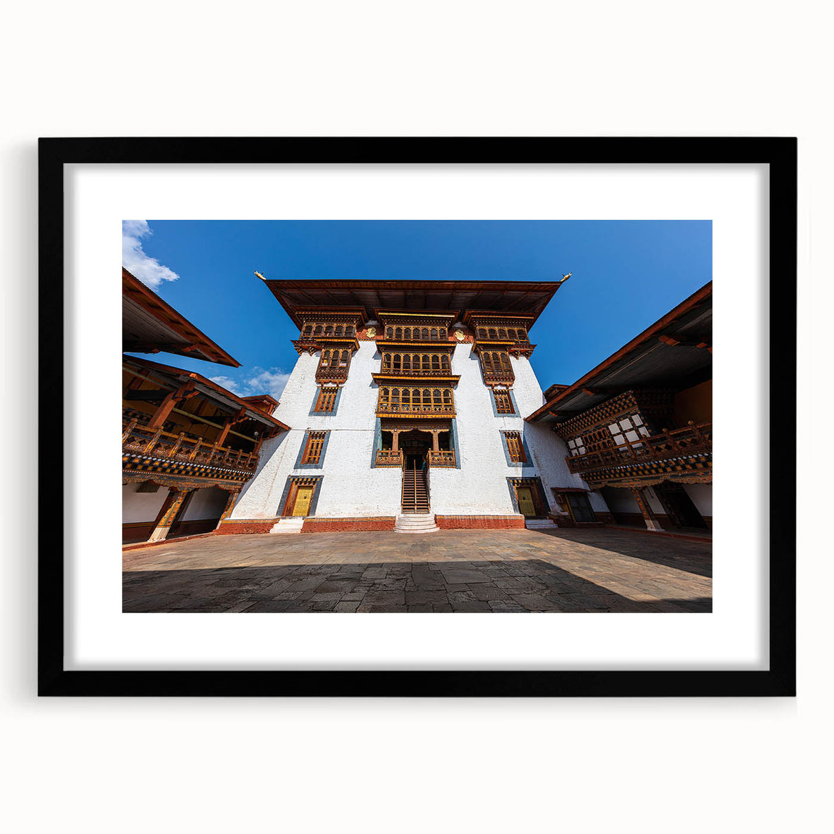 Abstract art print of a Bhutanese landscape in vibrant colors on a large textured canvas, framed in black.