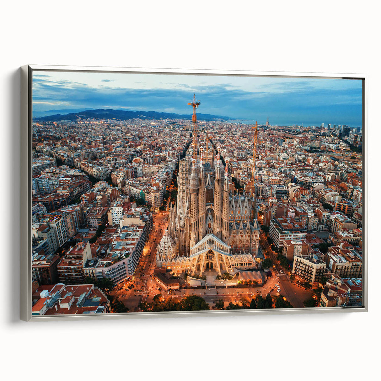 Landscape art painting of Barcelona featuring colorful buildings and a black sky, presented on a silver-framed canvas.