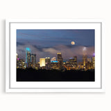 Abstract art print of Charlotte skyline in muted gray and blue tones on a framed white mat, suitable for dining room decor.