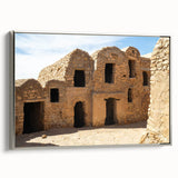 Framed canvas featuring a colorful vintage-style Moroccan landscape with vivid blue and orange tones.