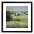 Framed landscape wall art depicting a serene countryside scene with vibrant green fields and a blue sky, featuring a sleek black frame and white mat.