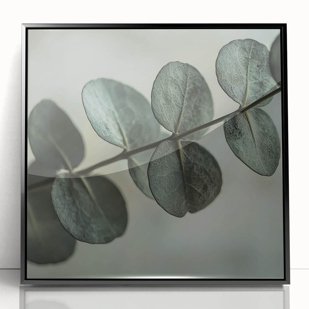 Large abstract wall art featuring close-up leaves in muted green tones, framed in black acrylic.
