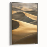 Framed canvas artwork showcasing serene sand dunes in soft beige and golden hues, elegantly displayed in a stylish silver frame, ideal for modern home decor.