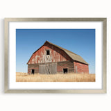 Silver-framed landscape barn design artwork with a white mat, showcasing a serene countryside scene. Ideal for home decor, this piece enhances rustic interiors.