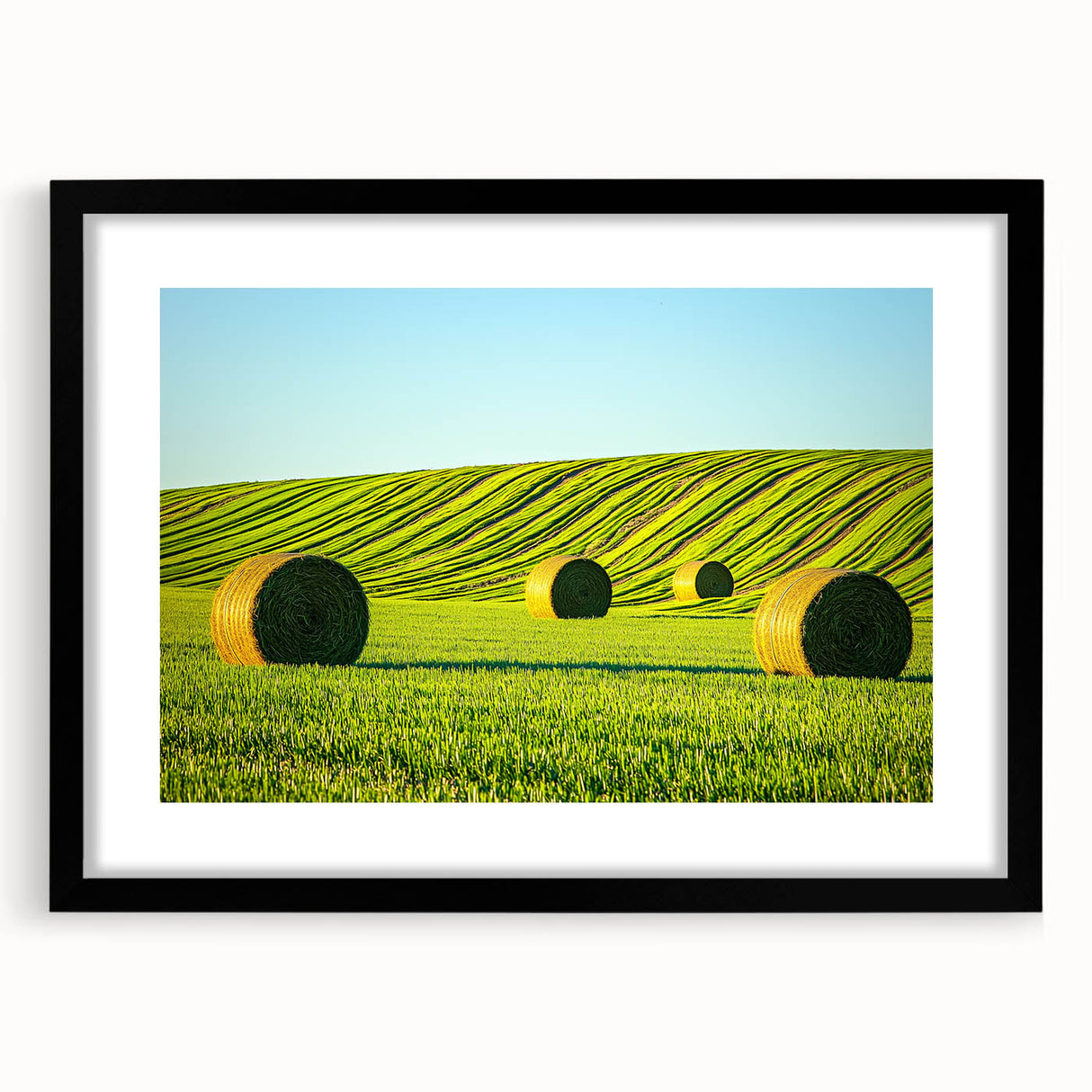 Black frame with a mat showcasing a vibrant landscape print featuring rolling green fields under a clear blue sky, ideal for home decor and nature lovers.
