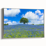 Framed canvas artwork showcasing a serene landscape with lush green fields and a vibrant sky, accented by a sleek silver frame, ideal for home decor.