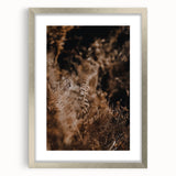 Textured abstract art print in warm autumnal hues on a silver-framed canvas, ideal for bedroom decor.