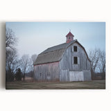 Stretched canvas print showcasing a picturesque landscape of a classic red barn surrounded by lush greenery, ideal for rustic home decor. Perfect for enhancing country-themed interiors and adding a touch of warm charm.