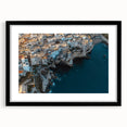 Framed landscape artwork showcasing dramatic cliffs against a vibrant sunset, presented in a sleek black frame with a white mat, perfect for modern decor.