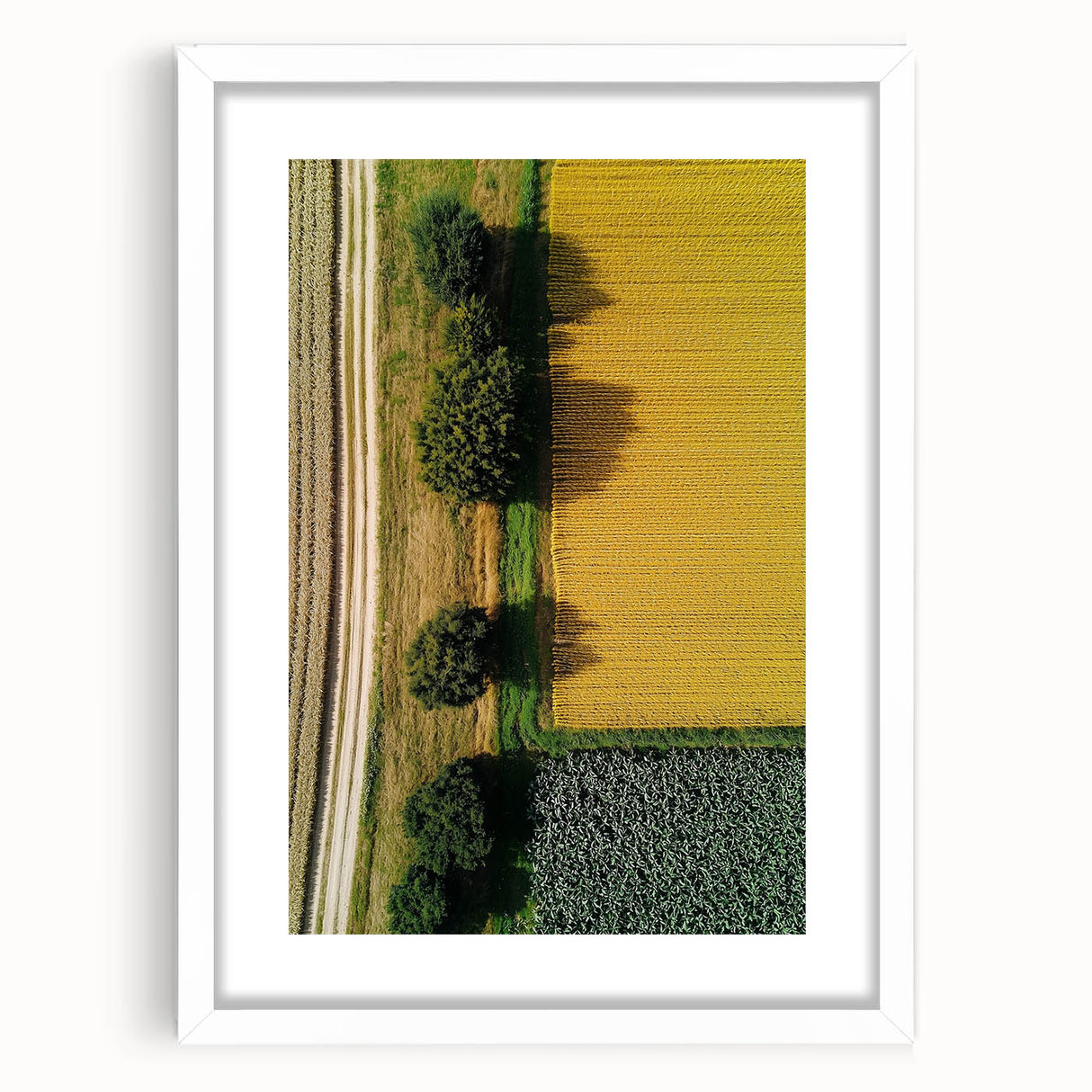 Framed landscape artwork in a white mat, showcasing a serene countryside scene with rolling hills and a clear blue sky, perfect for home decor.