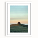 Framed landscape artwork showcasing a serene countryside scene, featuring vibrant green fields and a clear blue sky, presented with a white mat for an elegant finish. Perfect for home decor enthusiasts seeking to enhance their living space with nature-inspired art.