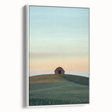 Framed canvas artwork depicting a serene countryside landscape with lush green fields and soft blue skies, presented in a sleek white frame for elegant home decor.