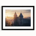 Framed landscape artwork showcasing a majestic castle surrounded by lush greenery, presented in a sleek black frame with a white mat, ideal for home decor.