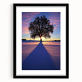 Black-framed landscape art print showcasing a serene countryside scene with vibrant greenery and rolling hills, accented by a white mat, ideal for home decor.