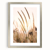 Abstract textured art print in warm orange and yellow tones, framed in silver, suitable for bedroom decor.