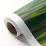 Rolled canvas artwork showcasing a serene countryside landscape, featuring vibrant green fields, a clear blue sky, and distant hills, ideal for home decor.