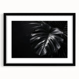 Botanical wall art featuring a Monstera design, framed in black with a mat, showcasing vibrant green leaves against a white background, ideal for modern decor.
