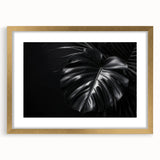 Framed botanical wall art featuring a Monstera plant design, showcasing vibrant green leaves and a gold frame, ideal for home decor and nature lovers.