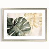 Framed botanical wall art showcasing a Monstera leaf design in vibrant green, set against a textured white background with a silver mat, ideal for modern decor.