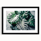 Framed botanical wall art featuring a Monstera leaf design, elegantly displayed with a black frame and white matting, perfect for modern home decor.