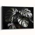 Framed botanical wall art featuring a Monstera leaf design on a black background, showcasing vibrant green hues and elegant framing, ideal for modern decor.