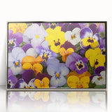 Framed botanical wall art featuring a vibrant pansy design in rich purple and yellow hues, elegantly displayed with a sleek silver frame, perfect for home decor.