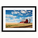 Framed wall art featuring a serene landscape scene with rustic barns, set in a black frame with a white mat, ideal for home decor enthusiasts seeking nature-inspired designs.