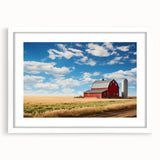 Framed wall art featuring a picturesque landscape of a rustic red barn surrounded by lush green fields, presented in a sleek white mat and frame, perfect for home decor.