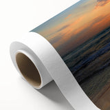 Vibrant rolled canvas artwork depicting a serene beach landscape at sunset, showcasing soft pink and orange hues, ideal for coastal home decor.