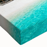 Close-up of a stretched canvas wall art featuring a vibrant beach landscape design with soft blues and sandy tones, perfect for coastal decor enthusiasts. This artwork adds a serene and calming atmosphere to any room, enhancing its aesthetic appeal.