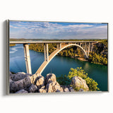 Framed canvas wall art depicting a serene landscape with a bridge, featuring a silver frame and vibrant colors, perfect for home decor or office space enhancement. This art piece adds a touch of elegance and tranquility to any room, making it an ideal choice for nature lovers and art enthusiasts.