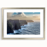 Framed landscape wall art featuring dramatic cliffs and serene ocean views, elegantly presented with a silver mat, perfect for enhancing modern home decor.