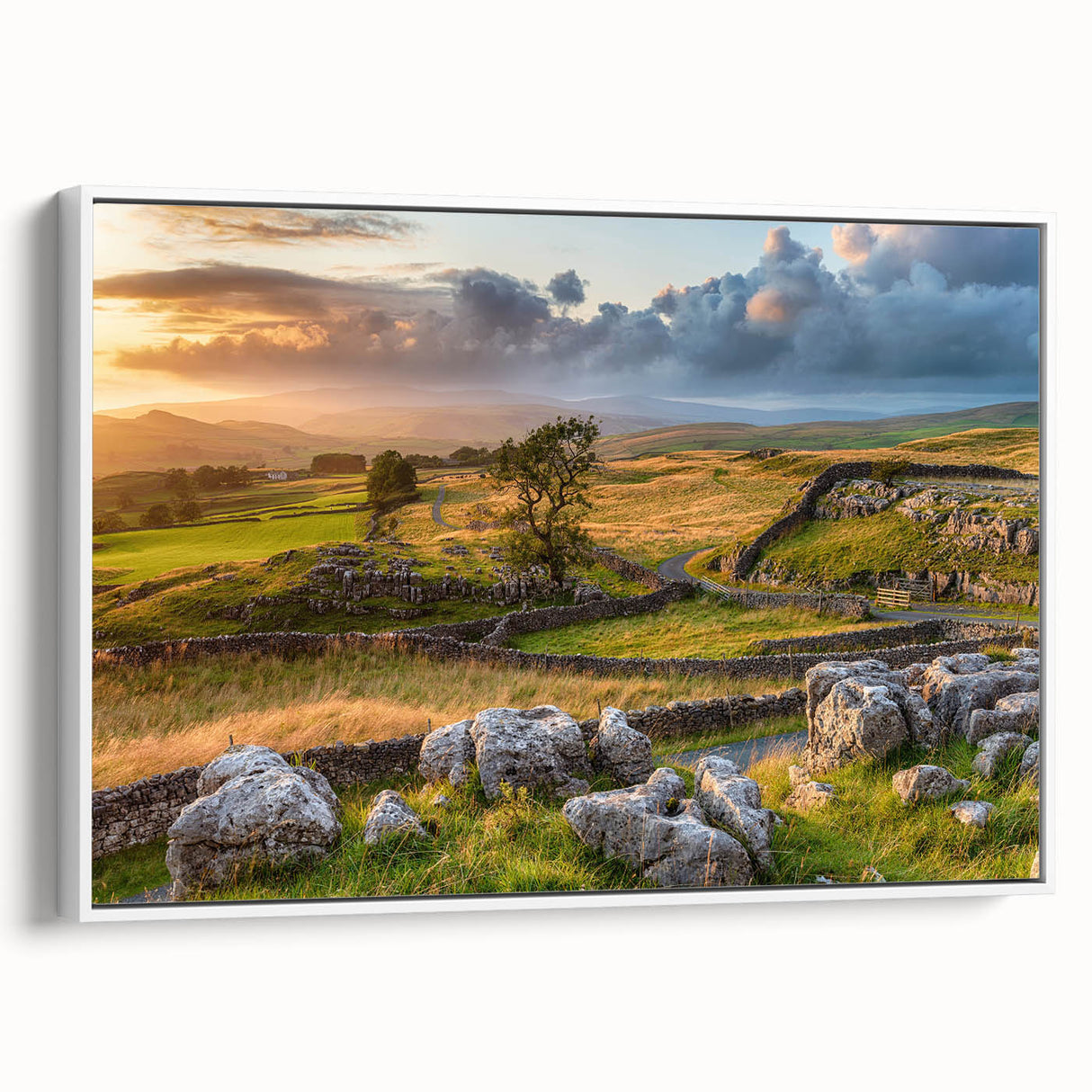 Framed canvas wall art depicting a serene countryside landscape with rolling hills and a vibrant sunset, featuring a white frame for modern aesthetics.