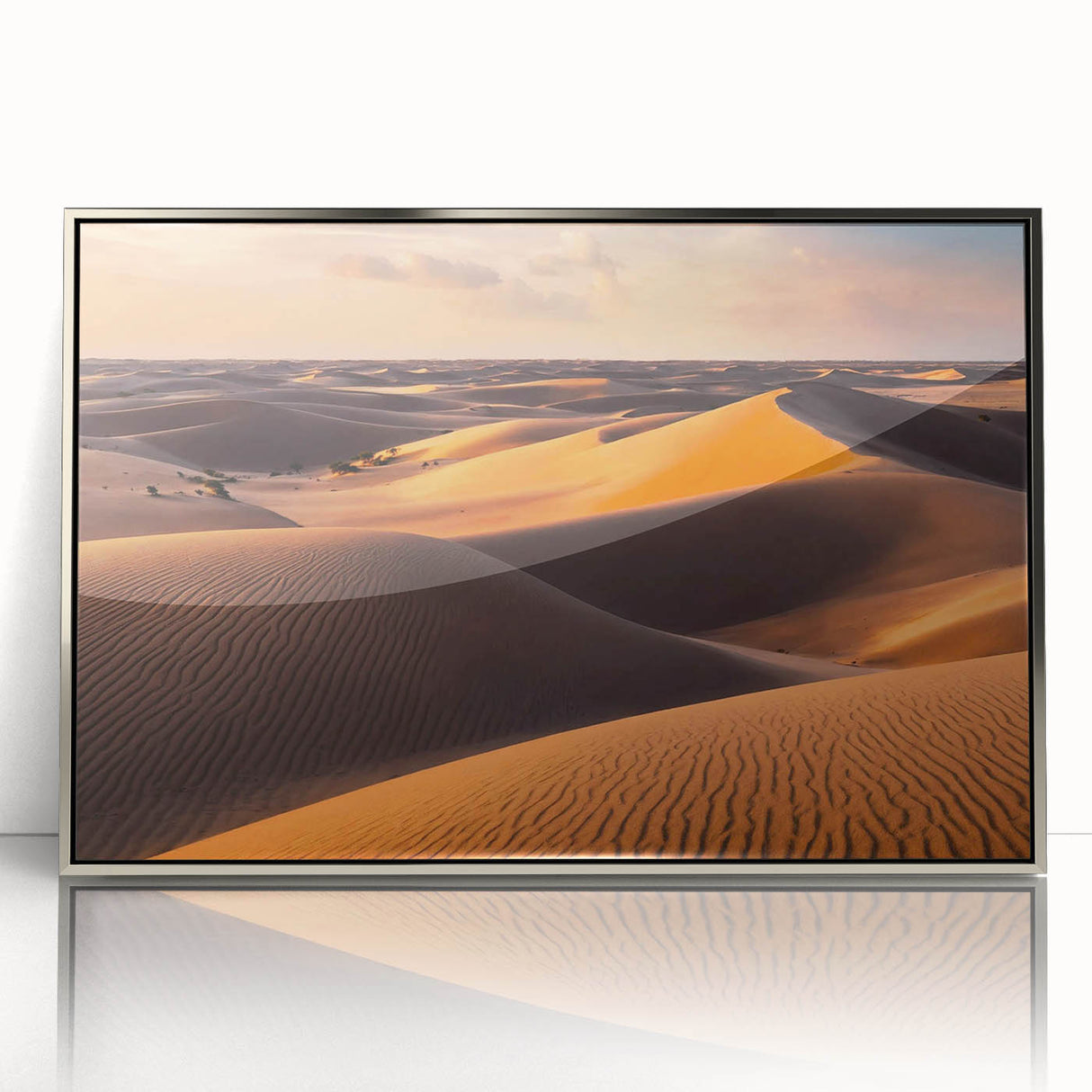 Framed acrylic wall art featuring a serene desert landscape with rolling dunes, showcased in a sleek silver frame, perfect for modern decor.