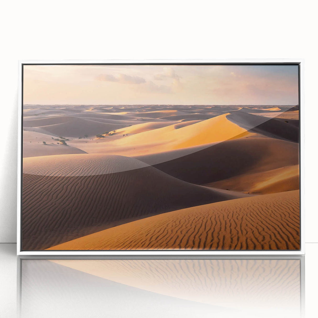 Framed wall art showcasing a serene desert landscape with rolling sand dunes, featuring a minimalist white frame that enhances the artwork's natural tones and textures. Ideal for home decor, this piece adds a touch of tranquility and elegance to any space.