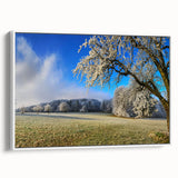 Framed canvas wall art depicting a serene landscape with lush green fields and a soft blue sky, elegantly showcased from a side view against a white background.