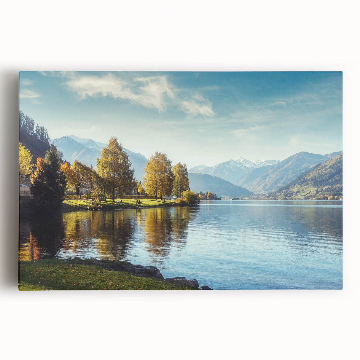 Stretched canvas wall art showcasing a serene landscape with a tranquil lake surrounded by vibrant trees and mountains, perfect for home decor enhancement.