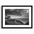 Framed wall art featuring a serene lighthouse landscape design in a black frame with a white mat, ideal for coastal-themed home decor. This elegant piece enhances interior spaces with its calming blue and green hues, perfect for living rooms or offices.