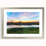 Framed wall art featuring a serene marsh landscape with vibrant greens and reflective water, elegantly presented with a silver frame and matting, ideal for home decor.